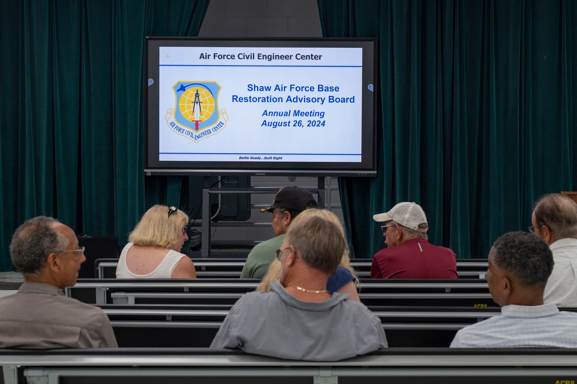 Community members sit in the audience waiting for a presentation.