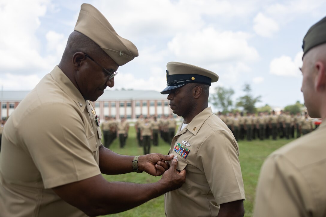U.S. Navy Capt. Arthur Wiggins, left, from Virginia and the chaplain of the 2nd Marine Aircraft Wing (MAW), pins the Fleet Marine Force (FMF) Warfare Insignia on Chief Religious Program Specialist Kenneth Armstead, from Alabama, with Marine Wing Headquarters Squadron (MWHS) 2, during a ceremony at Marine Corps Air Station Cherry Point, North Carolina, Aug. 30, 2024. The FMF Warfare Insignia is earned by Sailors assigned to FMF units and signifies that a Sailor has achieved a required level of excellence and proficiency with an enhanced comprehension of warfighting, mission effectiveness, and command survivability. (U.S. Marine Corps photo by Lance Cpl. Orlanys Diaz Figueroa)
