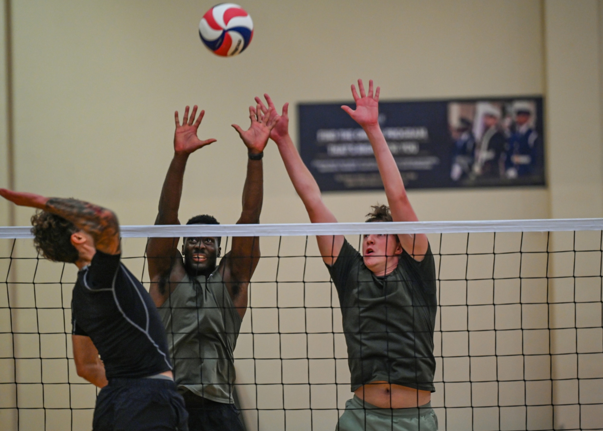 Men attempt to block a volleyball.