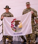 Col. (P) Lenny Williams, the Assistant Adjutant General – Army, and Commander of the Illinois Army National Guard, presents Capt. Andrew Mix, commander, Troop A, 2nd Squadron, 106th Cavalry Regiment, with a State of Illinois flag to carry with them on their deployment to the U.S. Africa Command area of responsibility.