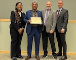 employees pose with certificate on stage