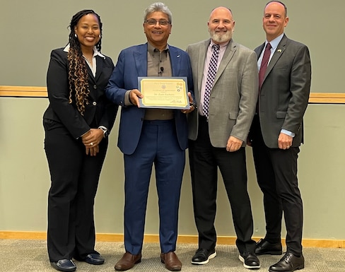 employees pose with certificate on stage