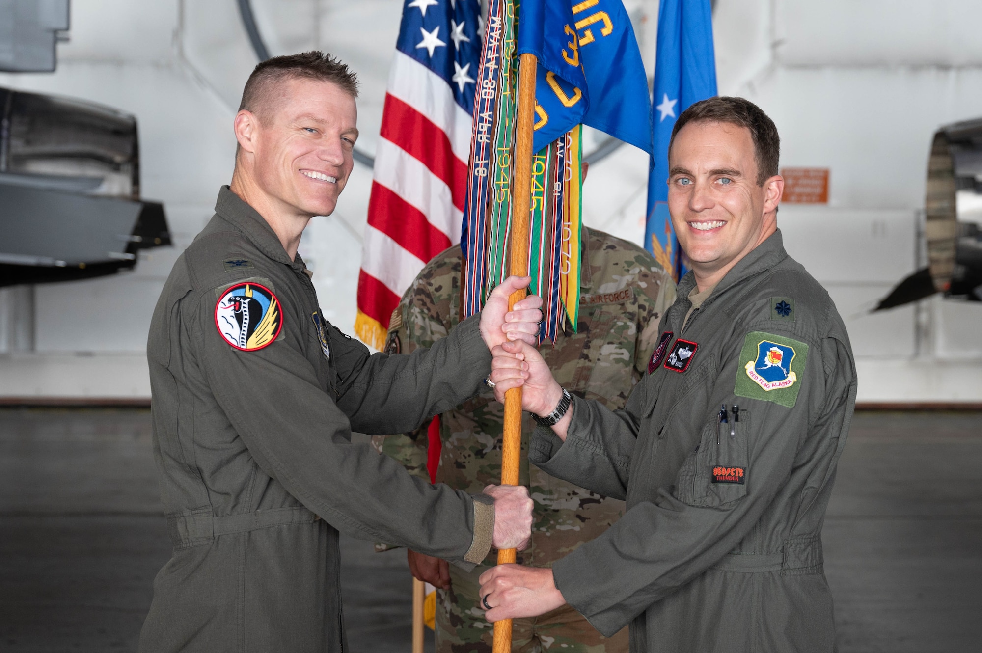 U.S. Air Force Col. Curtis Dougherty, left, 354th Operations Group commander, passes the guidon to Lt. Col. Eric Hakos, 353rd Combat Training Squadron incoming commander, during a change of command ceremony at Eielson Air Force Base, Alaska, Sep. 6, 2024.