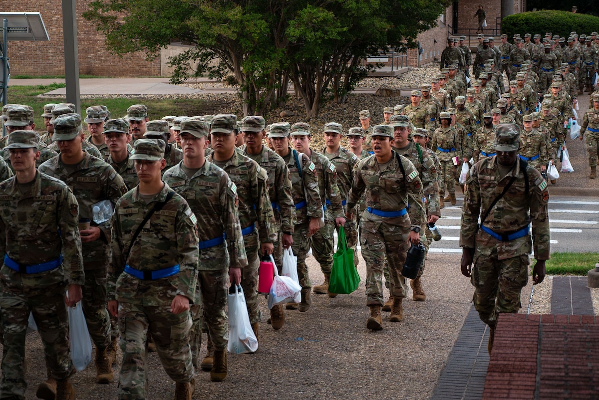 U.S. Air Force Airman 1st Class Lauro Garza, student leader assigned to the 315th Training Squadron, calls cadences while students march to class at Goodfellow Air Force Base, Texas, July 29, 2024. The troopwalk at Goodfellow allows student leaders to use precise facing movements to keep their flights aligned with the winding path from the dorms to the schoolhouse. (U.S. Air Force photo by Airman 1st Class Brian Lummus)