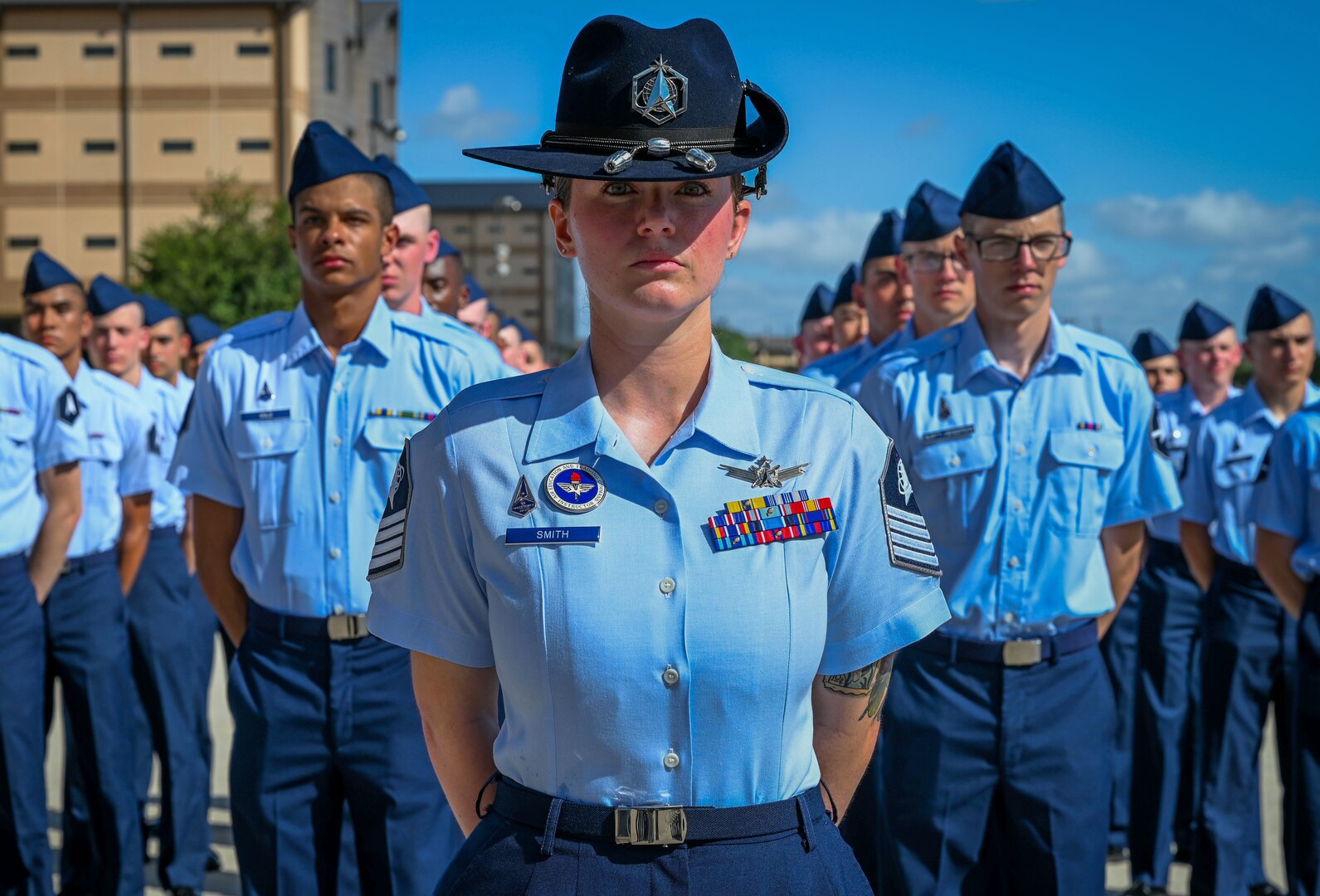 A group of guardians stands in formation outdoors, with a drill instructor standing front and center.