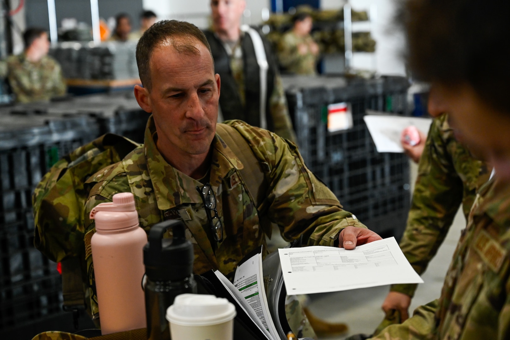 Master Sgt. Jeremy Cox, the consolidated toolkit noncommissioned officer in charge at the 157th Maintenance Group, hands an equipment accountability paper to a supply specialist, Sept. 7, 2024, at Pease Air Force Base, New Hampshire.