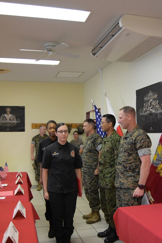 Cpl. Luana Barone Olivera followed by Lance Cpl. Darly Filsaime, turn to walk away after accepting the first-place award at the Marine Corps Installations Pacific’s Food Services Specialist of the Quarter competition, held at Combined Arms Training Center, Camp Fuji, August 30, 2024. The food service Marines are assigned to Marine Corps Base Hawaii. (U.S. Marine Corps photo by Song Jordan)