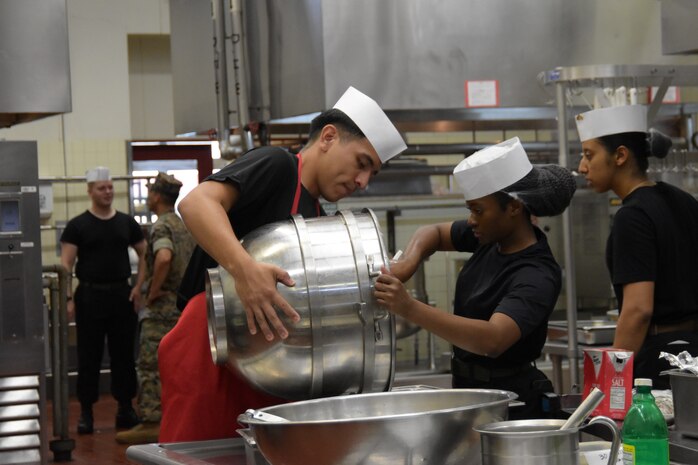 Lance Cpl. Alexis Martinez Nulasco holds a mixing bowl for Lance Cpl. Judy Dumas.