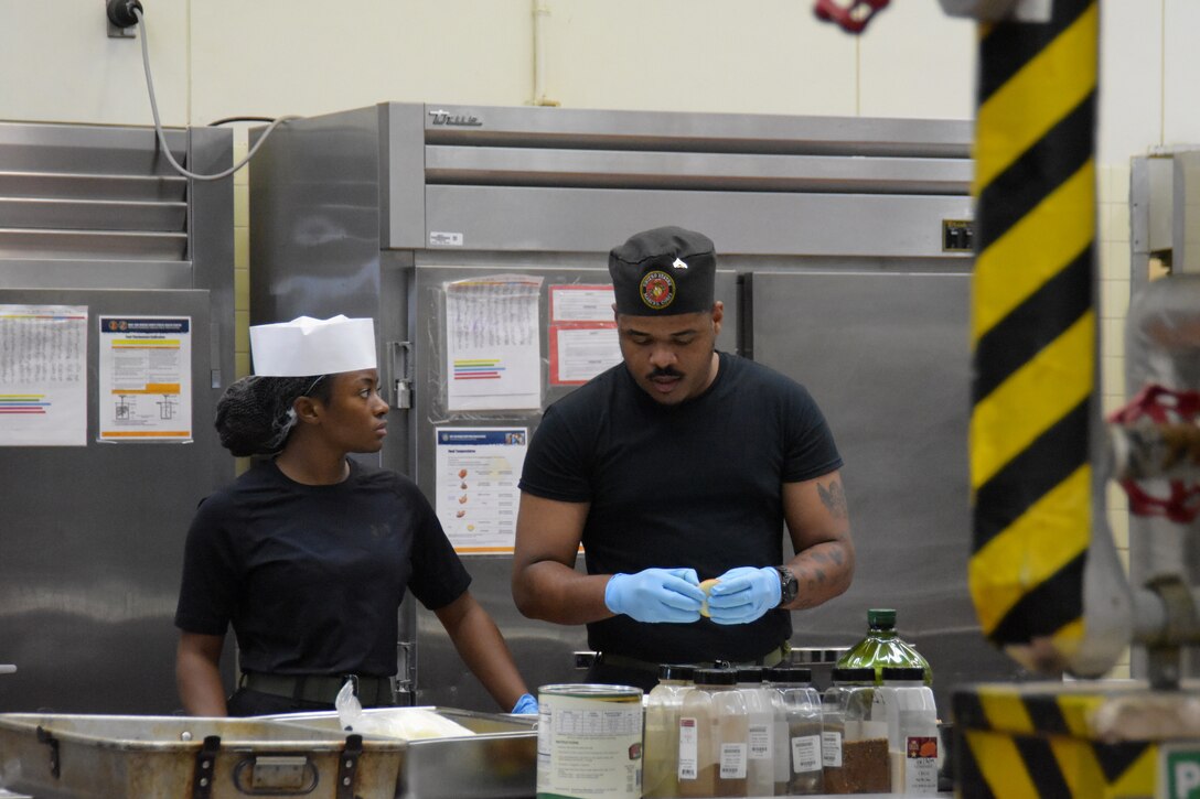 (Left to right) Food service Marines assigned to Camp Kinser, Lance Cpl. Shanera Coombs listens as Cpl. Lucky Anacletus talks during a prep session at the Marine Corps Installations Pacific’s Food Services Specialist of the Quarter competition, held at Combined Arms Training Center, Camp Fuji, August 29, 2024.  (U.S. Marine Corps photo by Song Jordan)