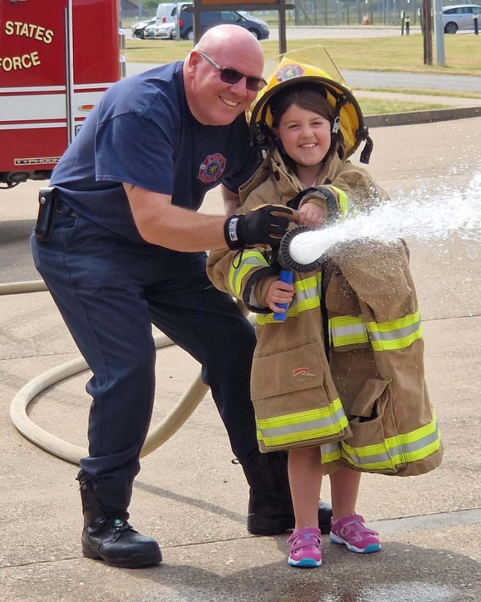Leon B. Duberry, 423rd RAF Alconbury/Molesworth firefighter/EMT, holds a fire hose with his niece