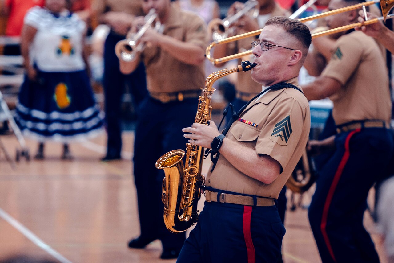 A Marine plays a musical instrument surrounded by others in a band.
