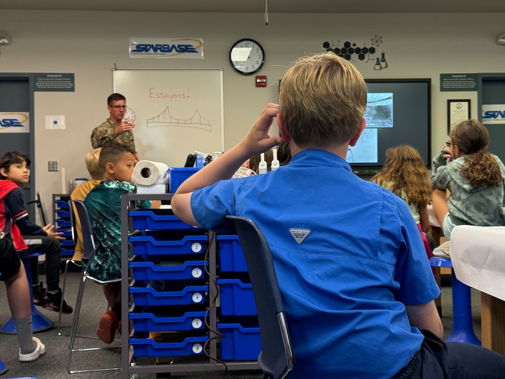 A group of students listen to a man in uniform provide a lecture.