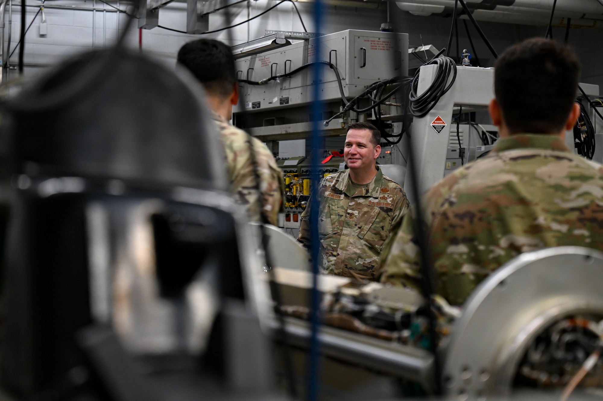 U.S. Air Force Chief Master Sgt. Gene Jameson III, U.S. Air Force Warfare Center command chief, receives a briefing from members of the 36th Electronic Warfare Squadron pod shop during a wing visit at Eglin Air Force Base, Florida, Aug. 29, 2024. The pod shop provides maintenance to electronic countermeasure pods that are used for testing of reprogrammed mission data files within the 36th EWS. (U.S. Air Force photo by Senior Airman Anna Smith)