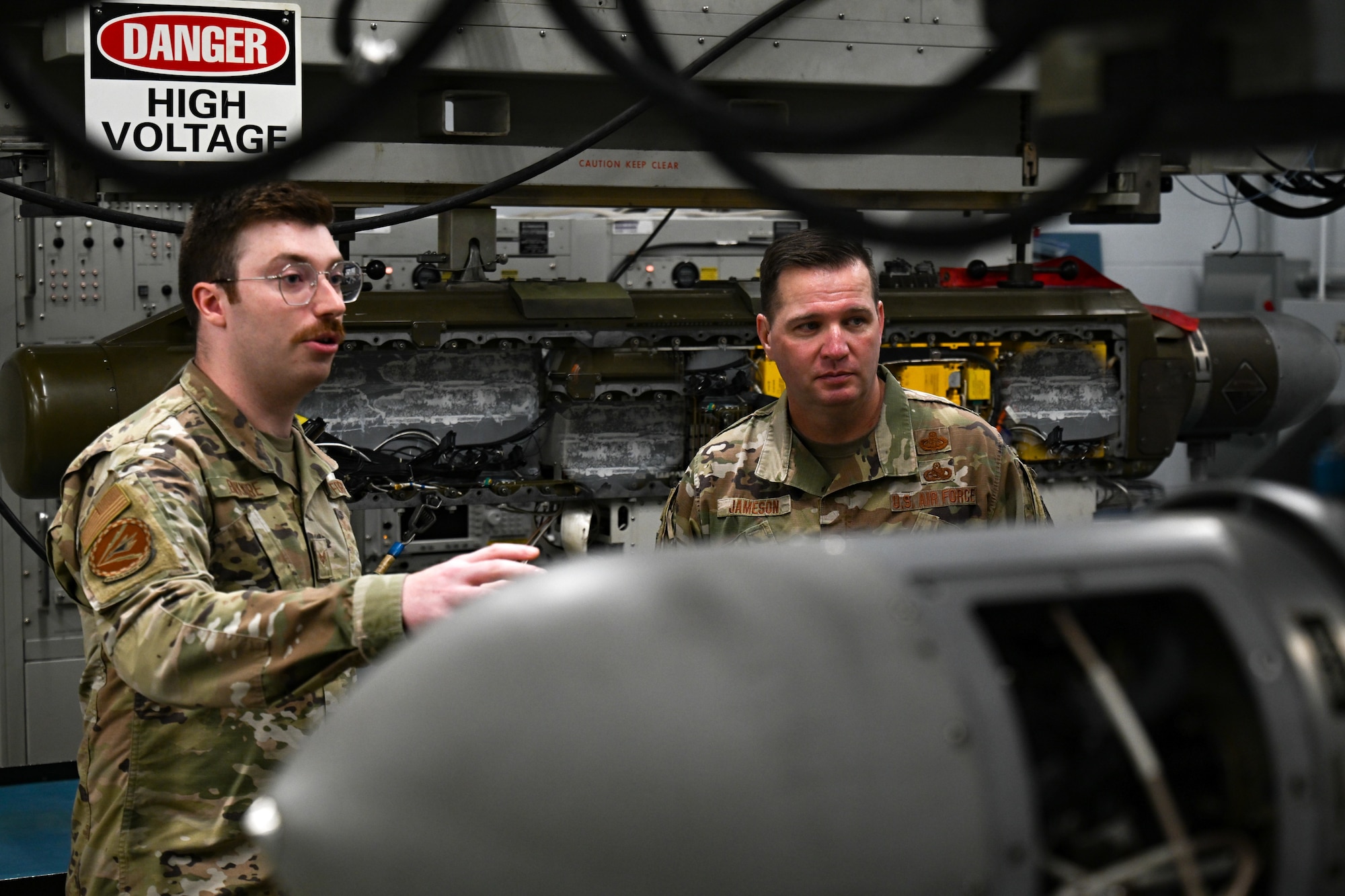 U.S. Air Force Senior Airman Joseph Birkmire, 36th Electronic Warfare Squadron EW systems journeyman, left, briefs U.S. Air Force Chief Master Sgt. Gene Jameson III, U.S. Air Force Warfare Center command chief, right, during a wing visit at Eglin Air Force Base, Florida, Aug. 29, 2024. The pod shop provides maintenance to electronic countermeasure pods that are used for testing of reprogrammed mission data files within the 36th EWS. (U.S. Air Force photo by Senior Airman Anna Smith)