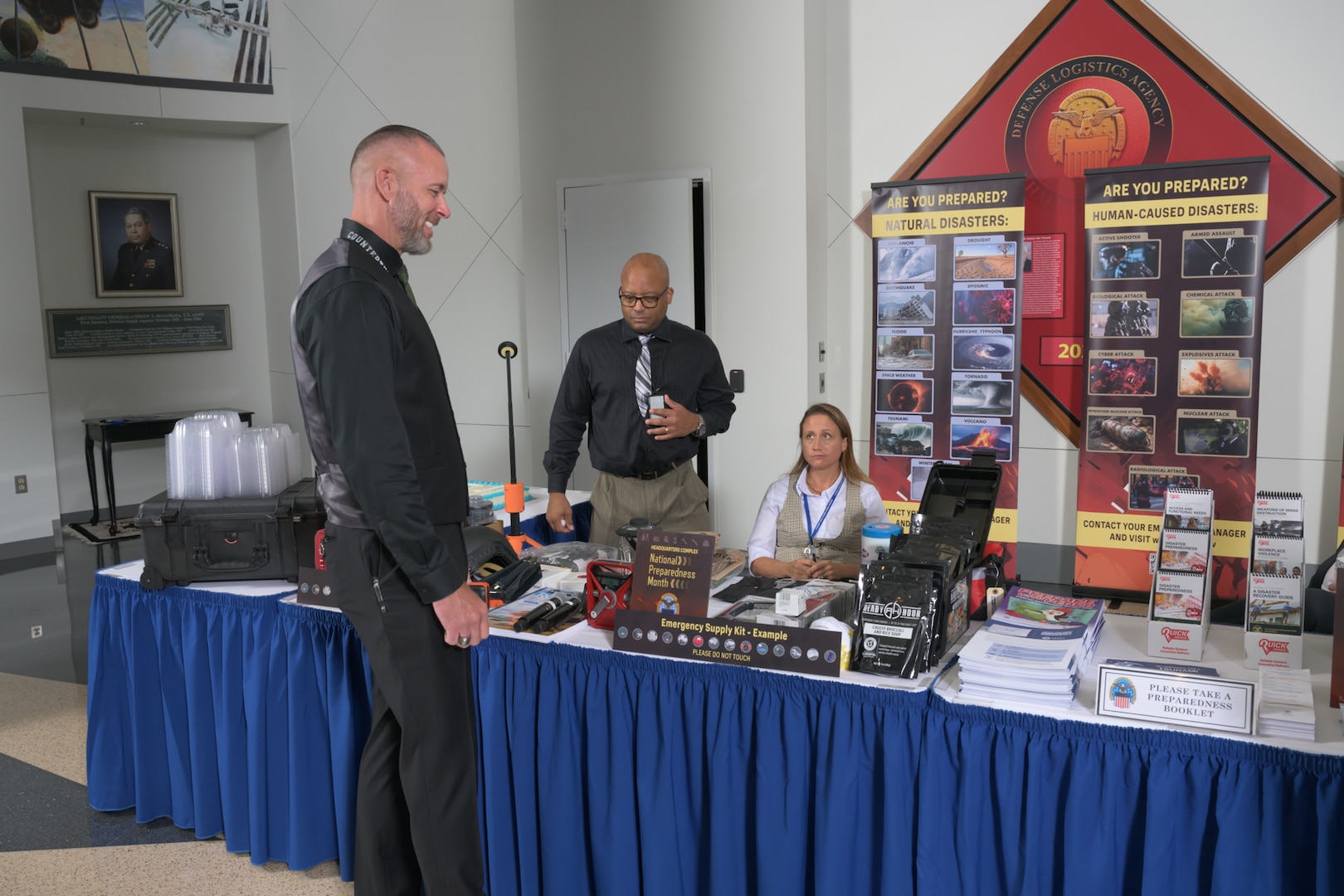 Defense Logistics Agency Emergency Management Program Manager James Johnston, left, and Carlton Dickens, DLA Installation Management emergency manager, right, greet a vendor during the National Preparedness Month observance