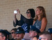 Janis Baucom and Michelle Efferson, 17th Training Wing honorary commanders, stand to view the Basic Military Training graduation ceremony at Joint Base San Antonio-Lackland, Texas, Sep. 5, 2024. U.S. Air Force Col. Angelina Maguinness, 17th Training Wing commander, invited Goodfellow Air Force Base’s Honorary Commanders to experience trainees joining the Air Force and becoming Airmen. (U.S. Air Force photo by Senior Airman Zach Heimbuch)