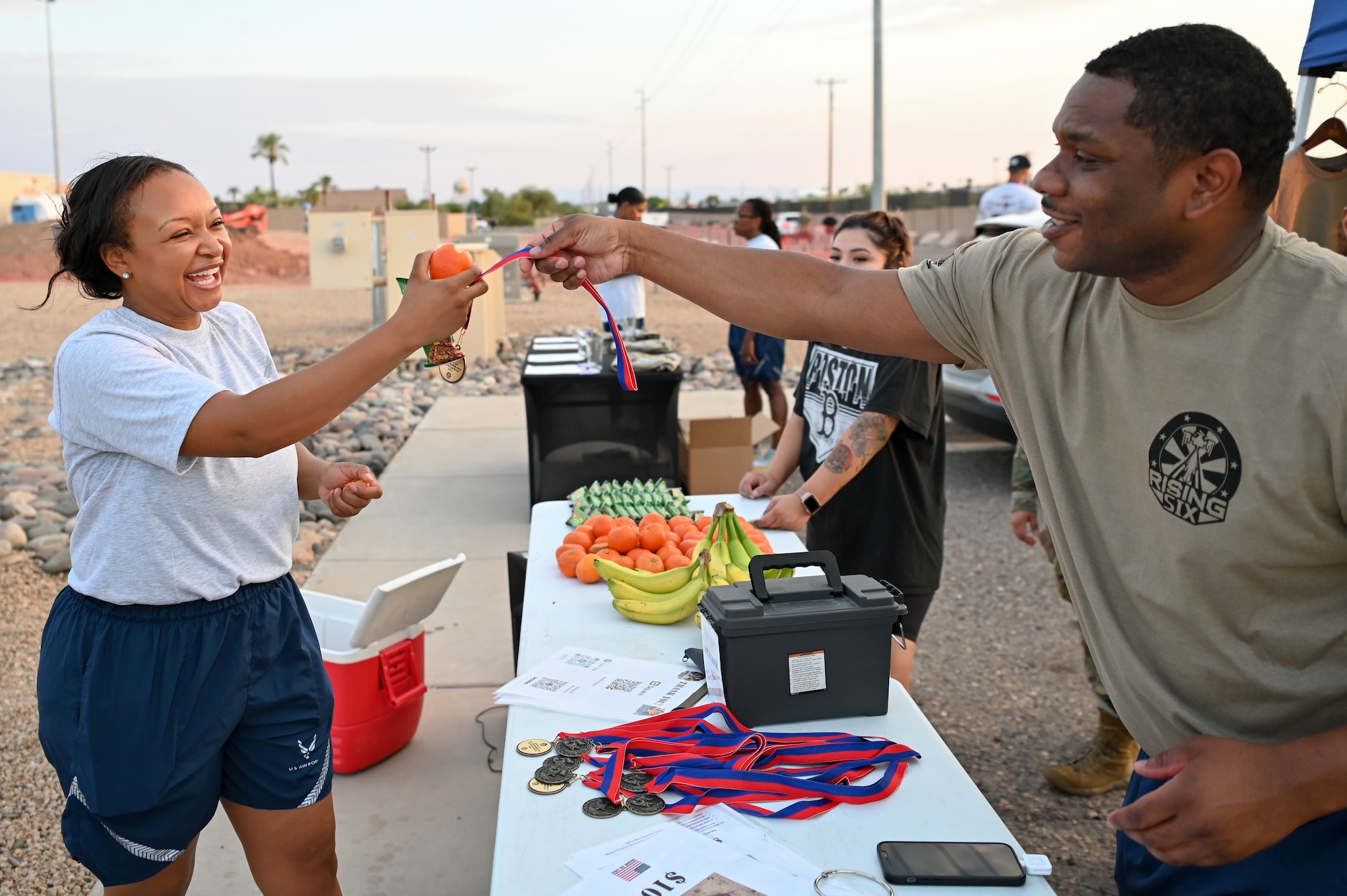 A participant in the 944th Fighter Wing's 9/11 Remembrance 5K receives a medal from an event organizer and Rising Six member after completing the run on Sept. 8, 2024, at Luke Air Force Base, Ariz. The Rising Six is an organization of junior enlisted personnel and played a critical role in supporting this event. (U.S. Air Force photo by Senior Airman Alexis Orozco)