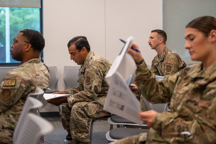In focus, Rivera-Ainaga hunches over to look at class material while others out of focus around him do the same