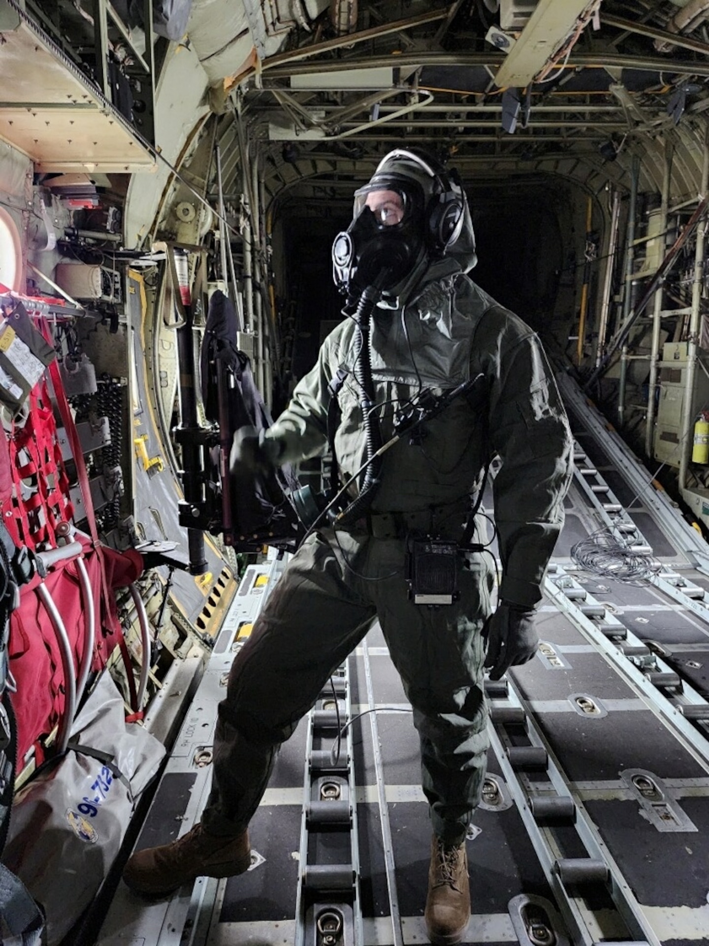 An Airmen stands in CBRN protective suit and mask inside the C-130H aircraft