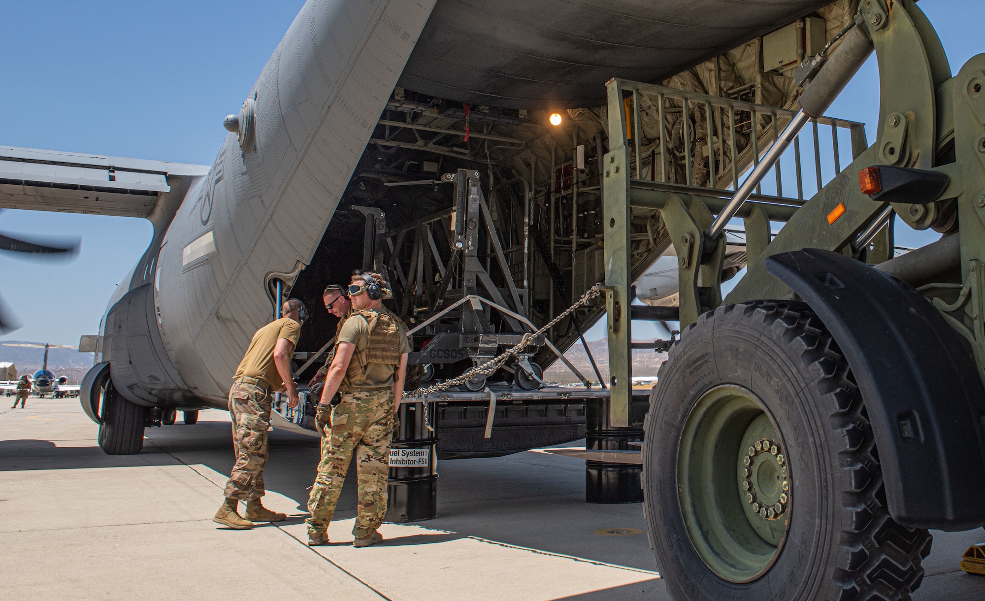 U.S. Airmen assigned to the 621st Contingency Response Squadron load barrels underneath a pallet for a combat offload operation during exercise Agile Flag 24-3 at Mojave, California, Aug. 8, 2024. The CRS works in small teams to safely and effectively establish a logistical supply chain in austere environments. During AGILE FLAG 24-3, the 23rd Wing provided the Air Expeditionary Wing leadership element, the Command and Control Force Element, and the Air Base Squadron at two separate locations exercising rapid insertion into theaters, establishing logistics and communications with theater C2, receipt of follow-on forces, mission generation, and combat power projection across all domains, while making critical decisions needed to remain agile. (U.S. Air Force photo by Airman 1st Class Sir Wyrick)