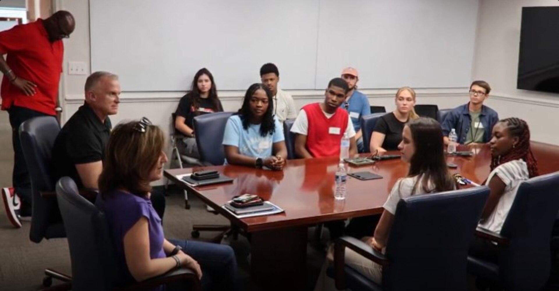 Students sit around a table with JPEO-CBRND leaders and talk