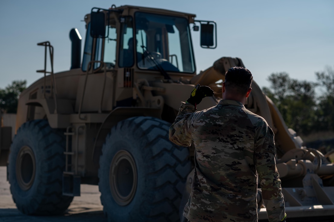 Airman in front of heavy machinery.