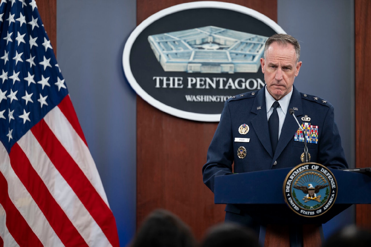 A man in a military uniform stands behind a lectern.