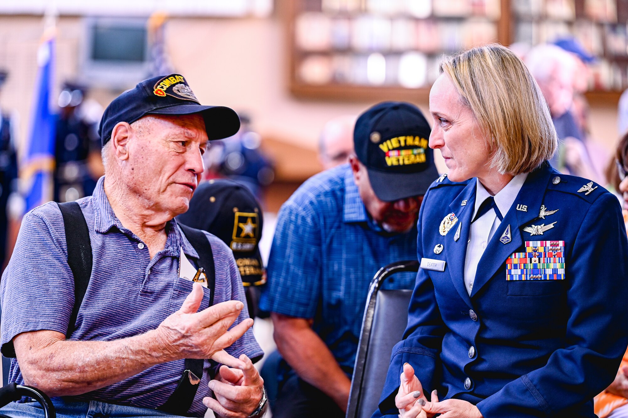 Uniformed woman listens intently to old retired veteran