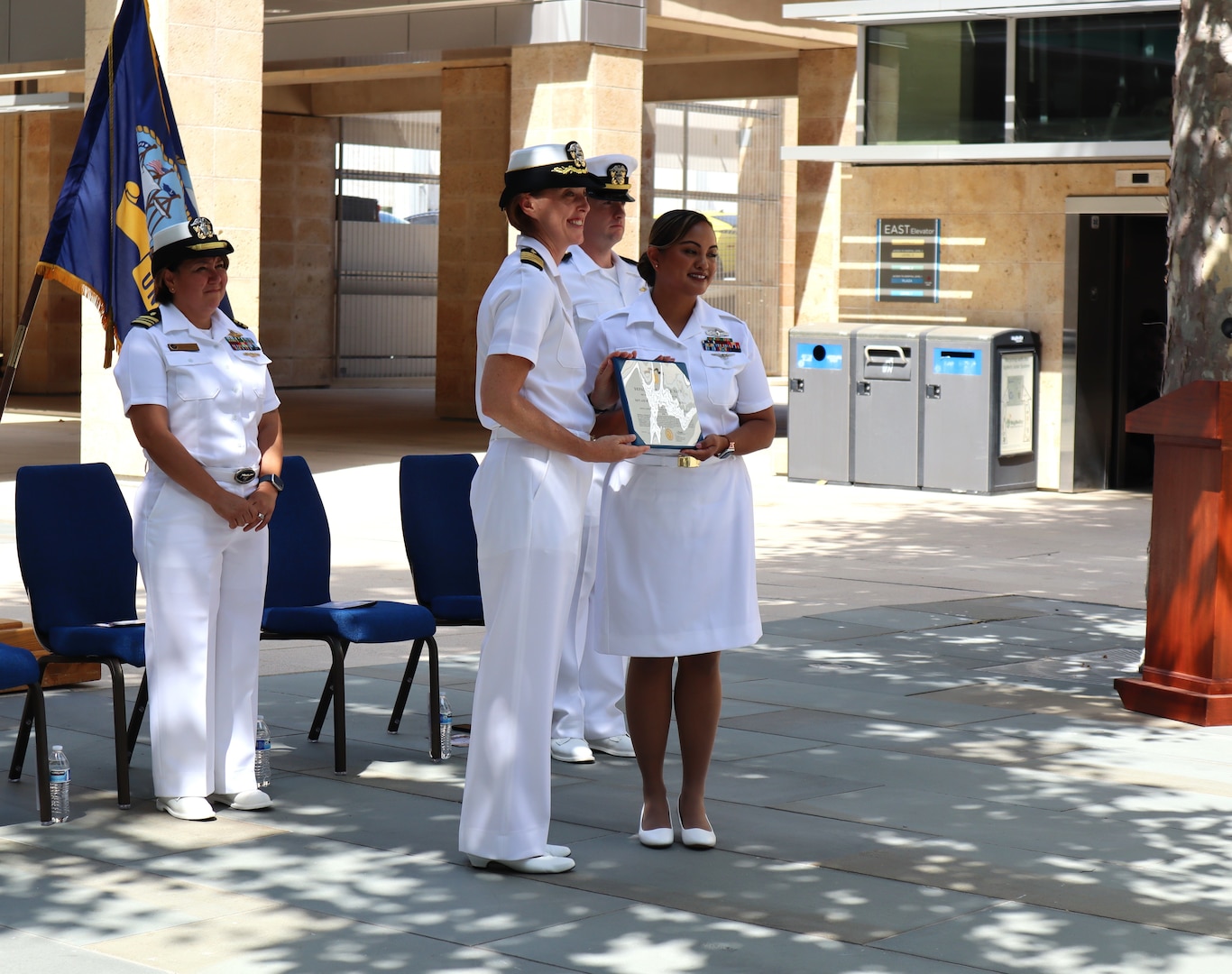 Navy Capt. Jenny Burkett, commander of Navy Medicine Readiness and Training Command Camp Pendleton, presents Hospital Corpsman 2nd Class Grace Joan Reveles with the Navy and Marine Corps Achievement Medal in recognition of her performance as the department leading petty officer for the Camp Pendleton Intrepid Spirit Center during Reveles’ commissioning ceremony held Sept. 6, 2024, on the hospital’s Medal of Honor Promenade. Moments later, having obtained both her associate degree and her bachelor’s degree in nursing while serving on active duty as a corpsman, Reveles was commissioned as an Ensign in the Navy Nurse Corps via the Direct Accession Program.