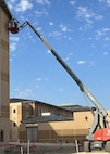 large crane against a building with a worker inside.