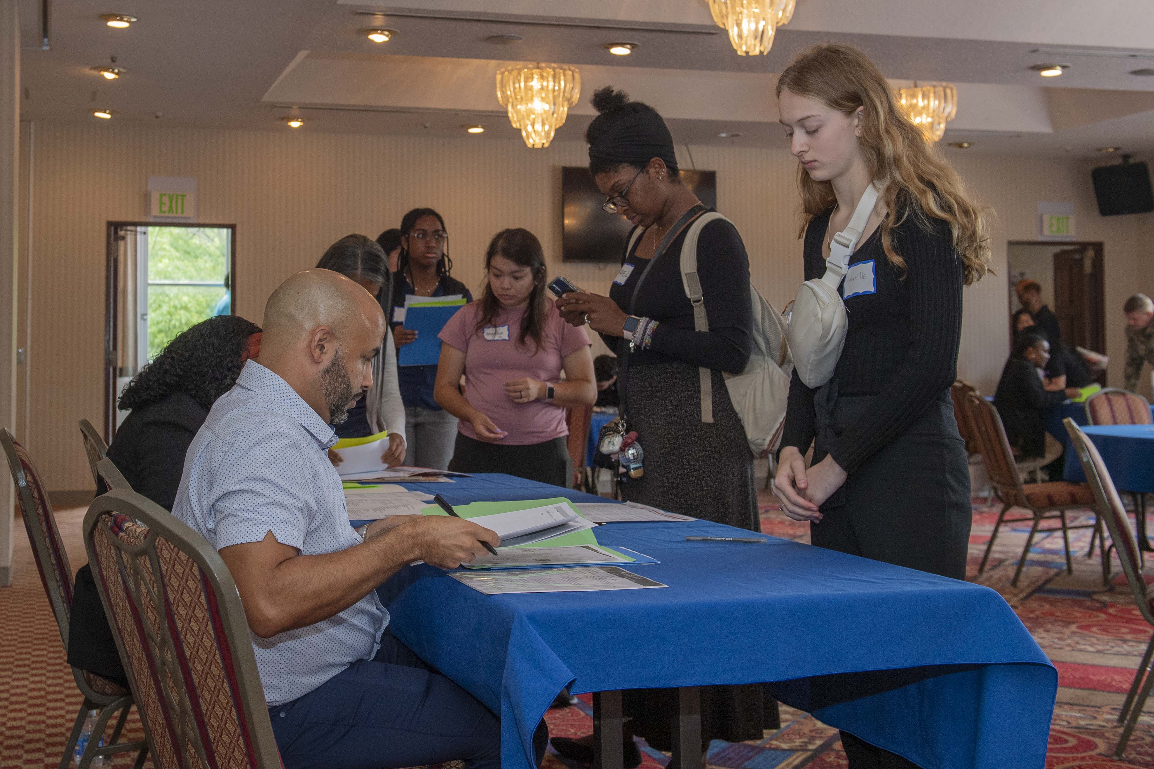 Fleet and Family Readiness staff members review base community members’ documents during the Child and Youth Programs, and Morale, Welfare, and Recreation hiring event at the installation's Officer's Club Sept. 4, 2024.