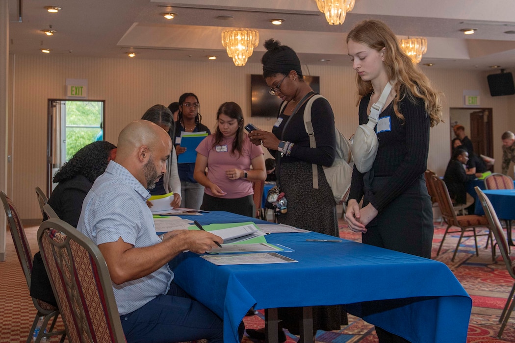 Fleet and Family Readiness staff members review base community members’ documents during the Child and Youth Programs, and Morale, Welfare, and Recreation hiring event at the installation's Officer's Club Sept. 4, 2024.