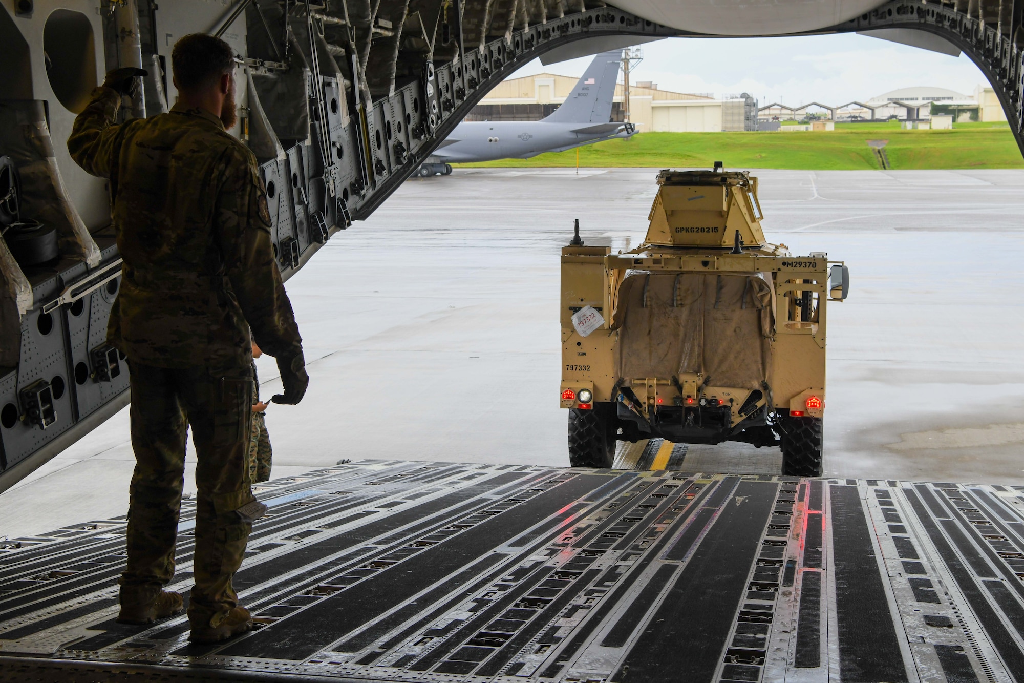 A loadmaster marshals a joint light tactical vehicle.