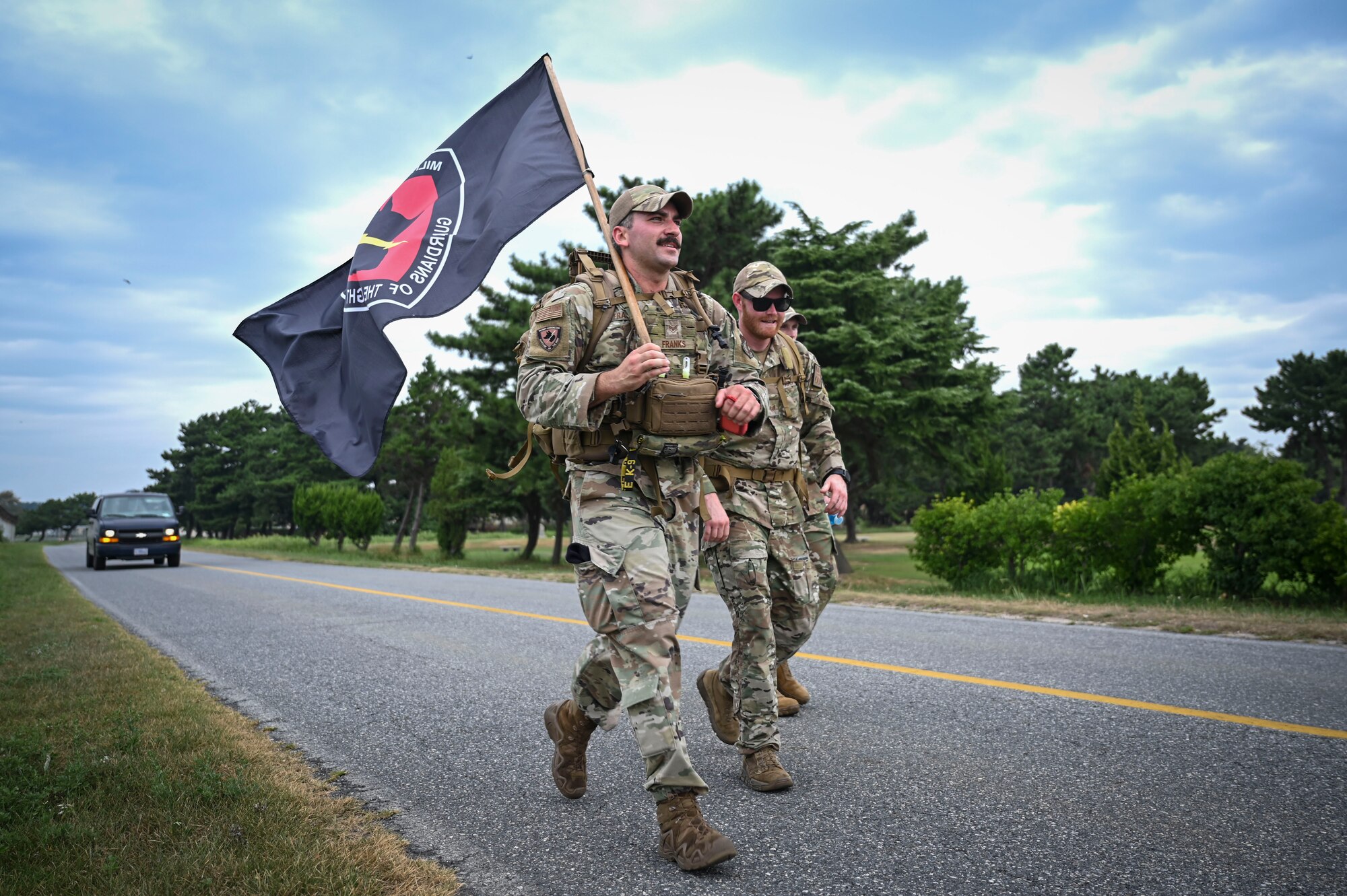 U.S. Air Force Staff Sgt. Logan Franks, left, 8th Security Forces Squadron military working dog (MWD) trainer, and Staff Sgt. Connor Washburn, right, 8th SFS MWD trainer supervisor, carry a MWD unit flag during the 9/11 Remembrance ruck.