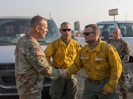 Brig. Gen. Alan R. Gronewold, the adjutant general of Oregon, presents a challenge coin to Spc. Rodney Chamberlain, an Oregon Army National Guard hand crew member, for exceptional performance fighting the Telephone Fire, Aug. 6, 2024, at the Harney County Fairgrounds fire camp.