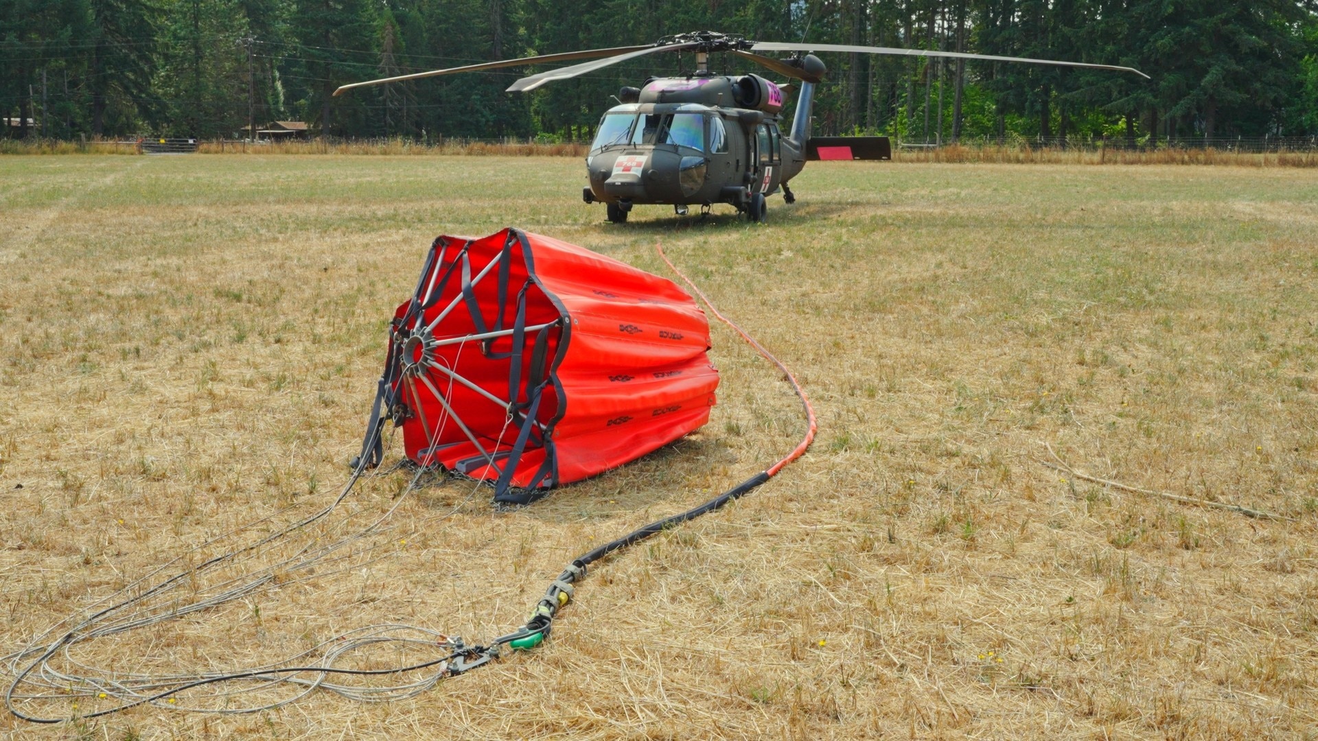 An Oregon Army National Guard HH-60 Black Hawk helicopter, equipped with a fire bucket, stands ready for wildfire suppression operations near Cottage Grove, Ore., Aug. 6, 2024. The aircraft was part of the Guard's aerial firefighting assets deployed to combat the Lane 1 fire complex.