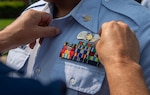 A petty officer 2nd class is in a dress uniform to receive a "pinning" of a brand new rank insignia for Response Operations Ashore.