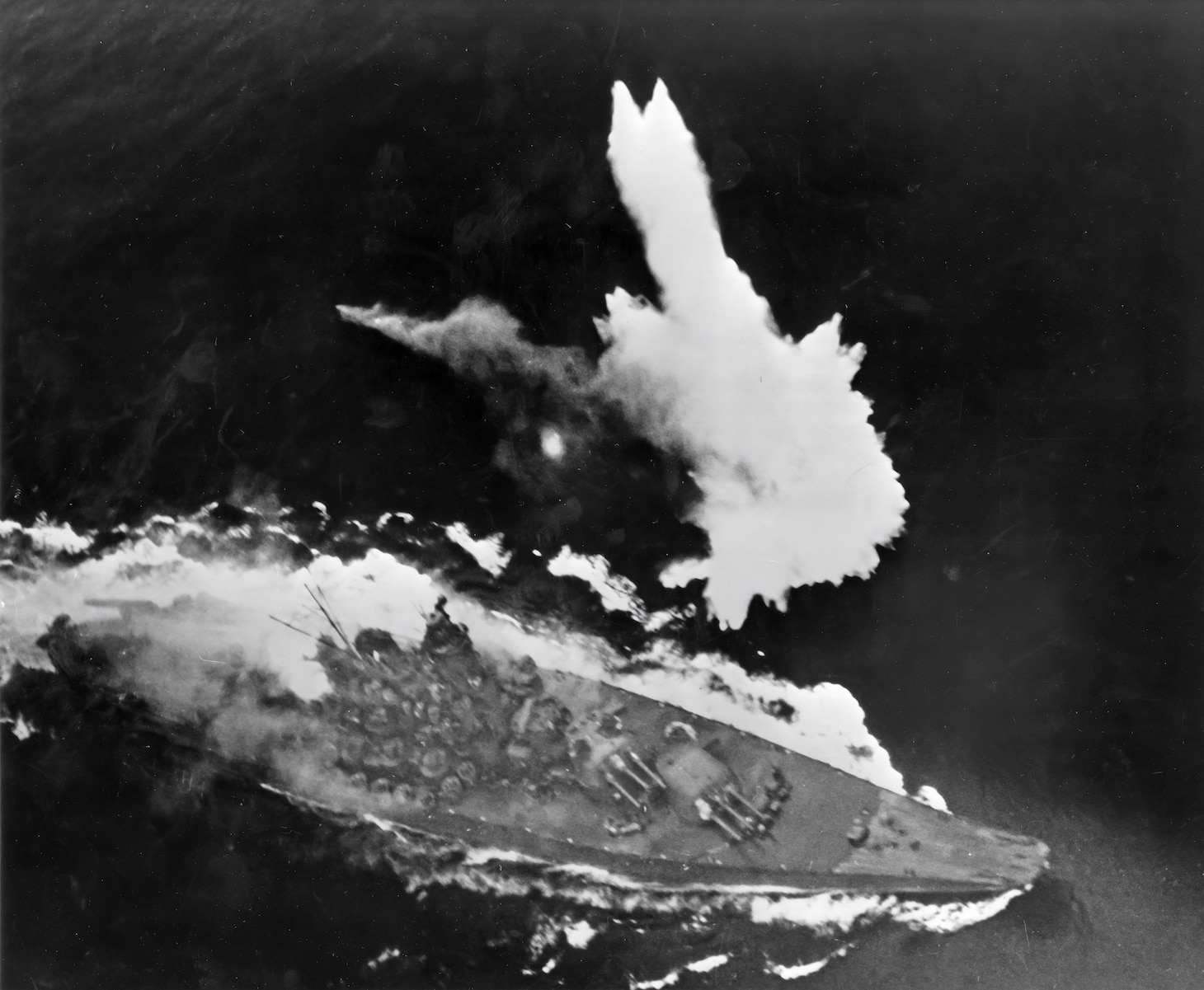 Yamato maneuvers frantically under attack as a bomb explodes off its port side. The fire in the area of the 6.1 inch turret can be clearly seen.