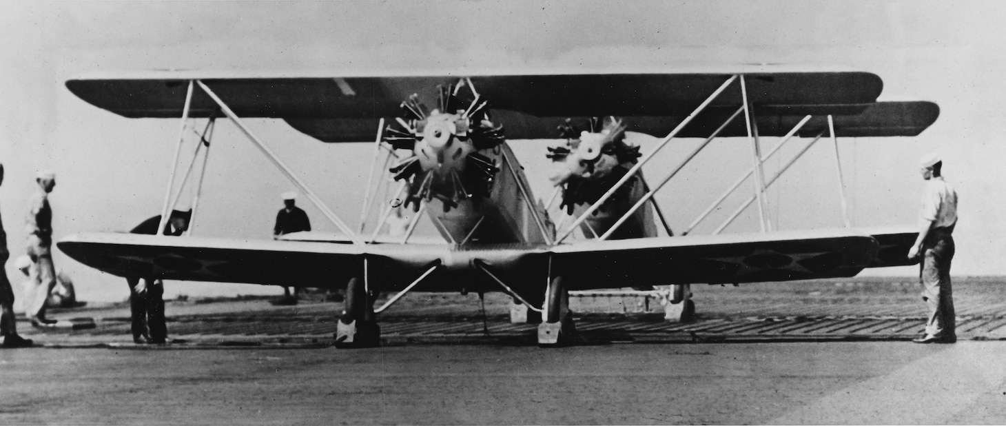 Two Naval Air Factory TS-1s of VF 1 warm up on the Langley’s flight deck in 1923. The TS-1 was the first squadron fighter aboard the Langley and was only armed with a single .30 caliber machine gun firing through the propeller. When the TS-1 was equipped with floats as a seaplane, it was craned over the side to the water and recovered the same way.