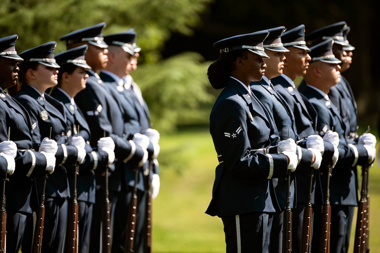 A group of airmen stand at attention on a field.