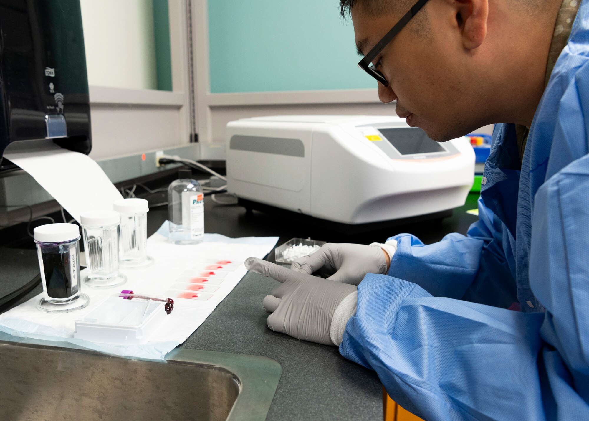 Medical technician creates slides for blood samples.