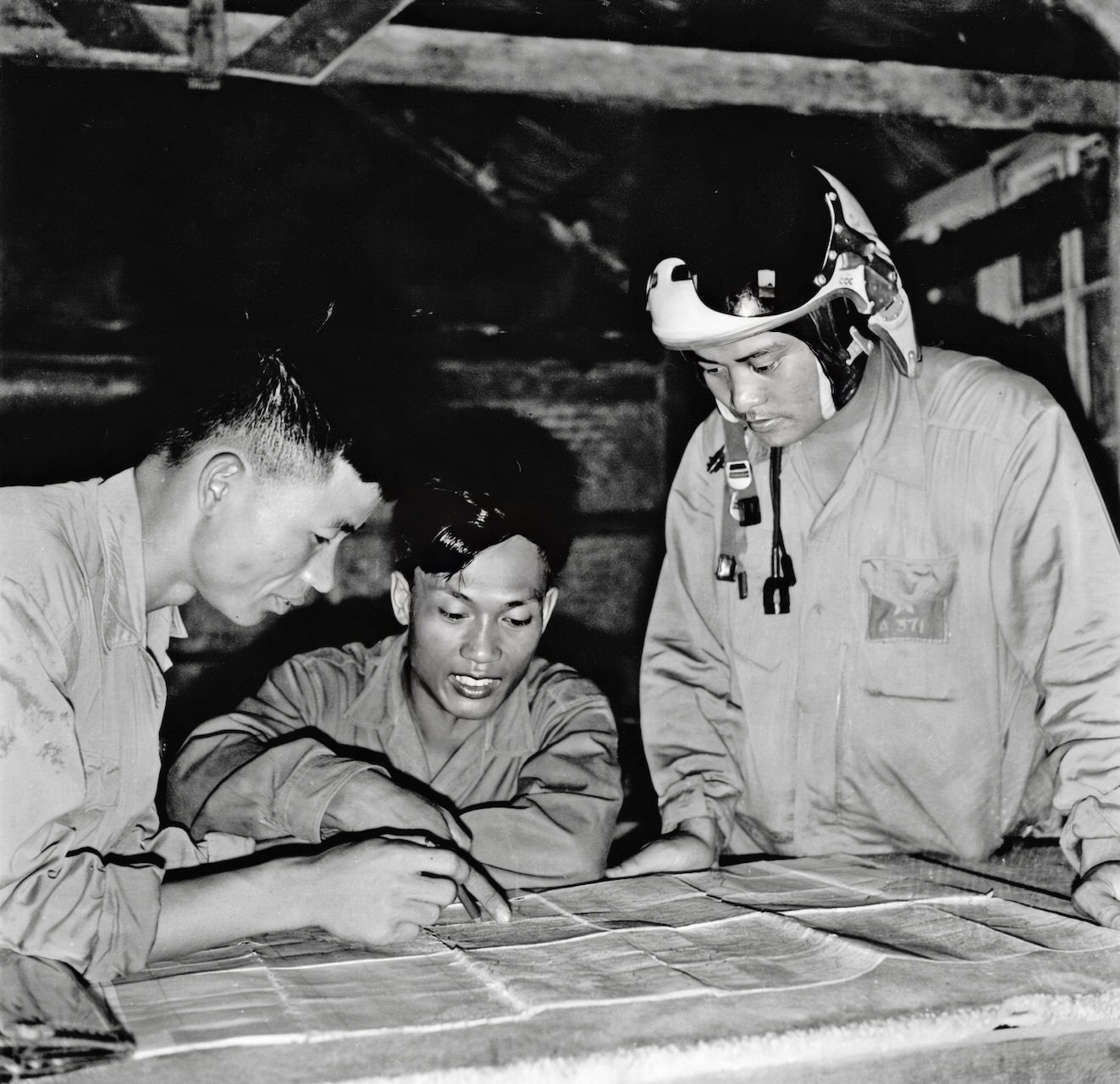 While two other squadron pilots go over their recent mission, Capt. Nguyen Van Coc, standing right, still wearing his flight helmet, listens. That day, Nov. 18, 1967, the two pilots shot down two U.S. Air Force F-105s, while Coc downed another F-105 with a missile.