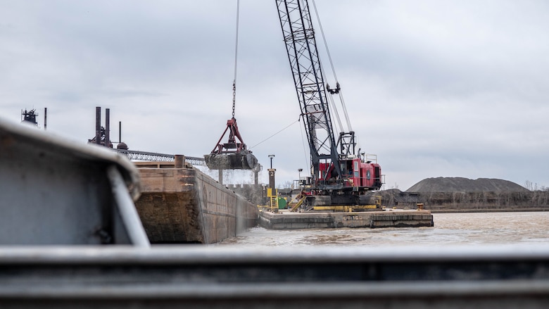 A crane on a barge dredges sediment from the federal navigation channel in Lorain Harbor and places it in a scow.