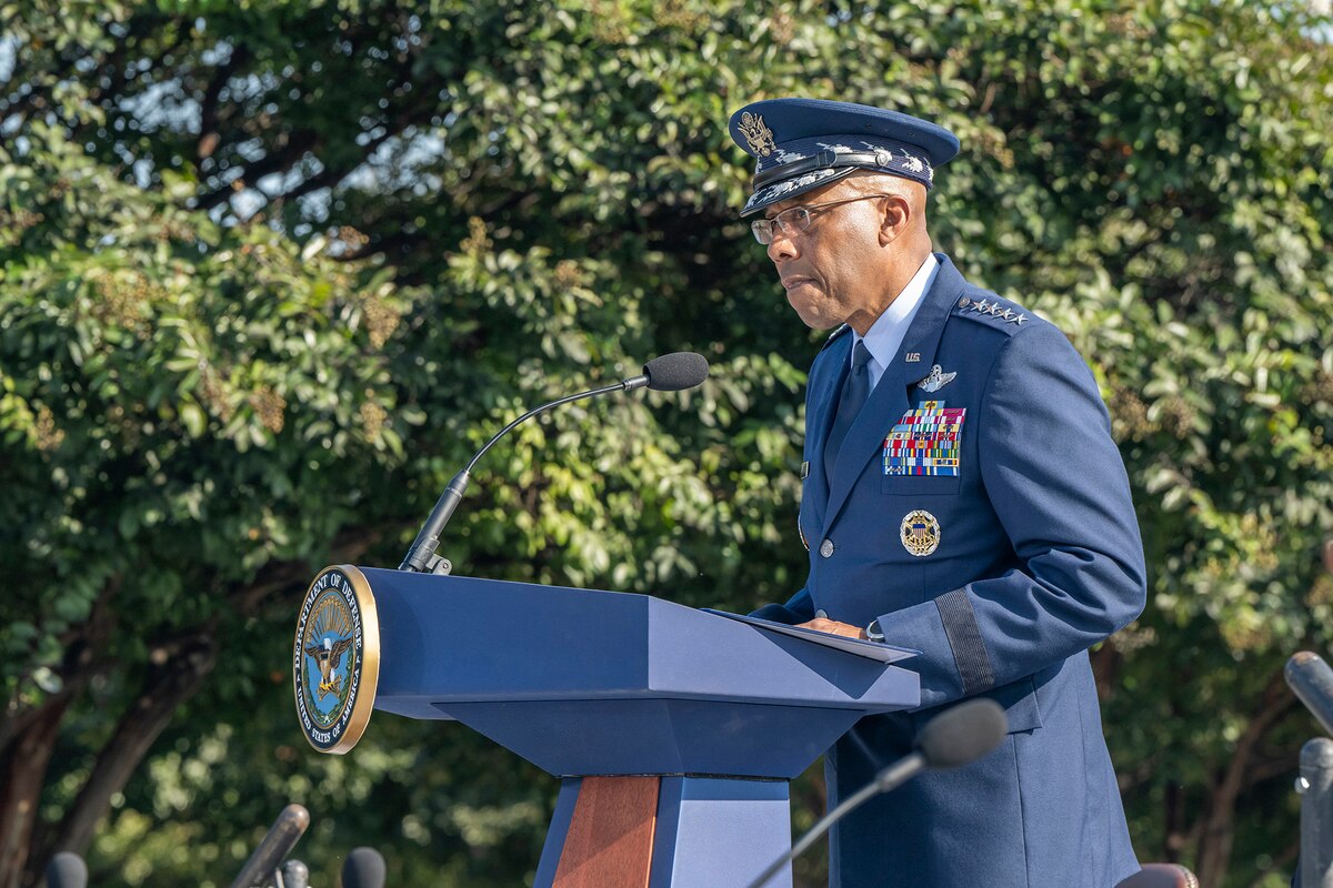 A person in a military uniform speaks at a lectern.