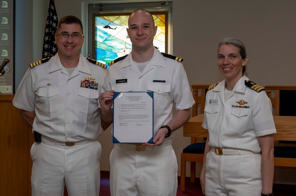 240910-N-DF135-1003 Lt. Kevin Hardiman (center) is presented with his graduation certificate by Capt. Brian Feldman, NMCP director/Navy Medicine Readiness and Training Command Portsmouth commander, and Cmdr. Robyn Treadwell, NMCP’s Mental Health director.  Hardiman will be stationed at Navy Medicine Readiness and Training Unit Portsmouth, New Hampshire.