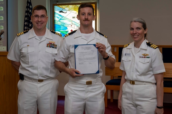 240910-N-DF135-1004 Lt. James O’Connor (center) is presented with his graduation certificate by Capt. Brian Feldman, NMCP director/Navy Medicine Readiness and Training Command Portsmouth commander, and Cmdr. Robyn Treadwell, NMCP’s Mental Health director. O’Connor will be stationed at Navy Medicine Readiness and Training Command Oak Harbor, Washington.