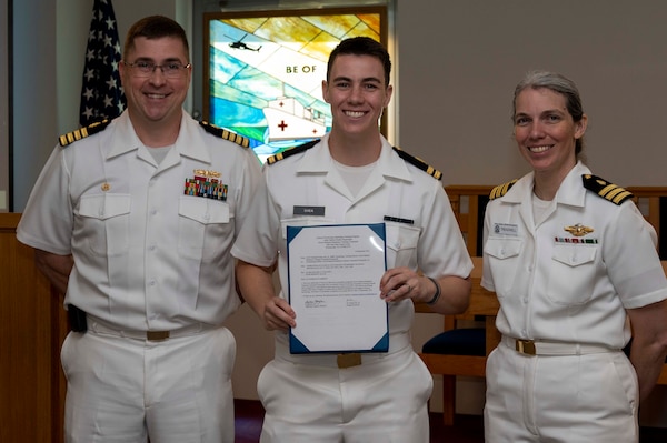 240910-N-DF135-1006 Lt. Kris Shea (center) is presented with his graduation certificate by Capt. Brian Feldman, NMCP director/Navy Medicine Readiness and Training Command Portsmouth commander, and Cmdr. Robyn Treadwell, NMCP’s Mental Health director.  Shea will be stationed at Navy Medicine Readiness and Training Unit Groton, Connecticut.