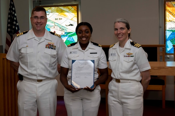 240910-N-DF135-1007 Lt. Sherly Smith (center) is presented with her graduation certificate by Capt. Brian Feldman, NMCP director/Navy Medicine Readiness and Training Command Portsmouth commander, and Cmdr. Robyn Treadwell, NMCP’s Mental Health director.  Smith will be stationed at Navy Medicine Readiness and Training Unit Iwakuni, Japan.