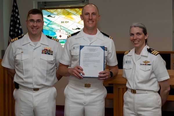 240910-N-DF135-1008 Lt. Kade Thornton (center) is presented with his graduation certificate by Capt. Brian Feldman, NMCP director/Navy Medicine Readiness and Training Command Portsmouth commander, and Cmdr. Robyn Treadwell, NMCP’s Mental Health director.  Thornton will be stationed at Embedded Mental Health Postdoctoral Fellowship, Portsmouth, Virginia.