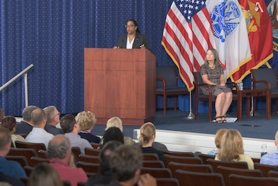 Woman on stage speaks to audience during fiscal year 2024 ceremony.